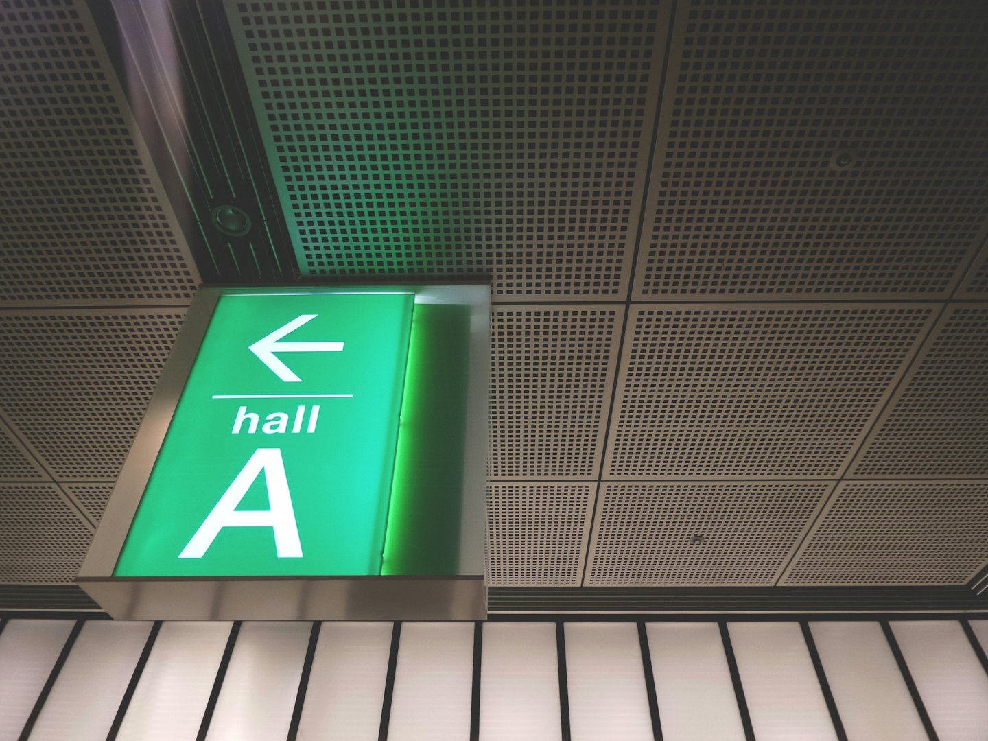A green directional sign for hall A hanging from the ceiling.