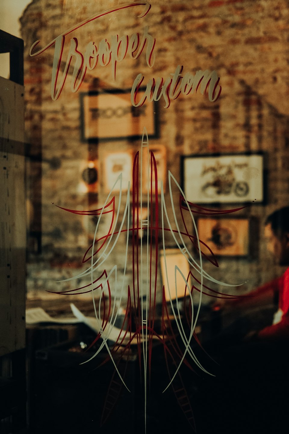 Custom hand lettering and pin striping art on a storefront window.