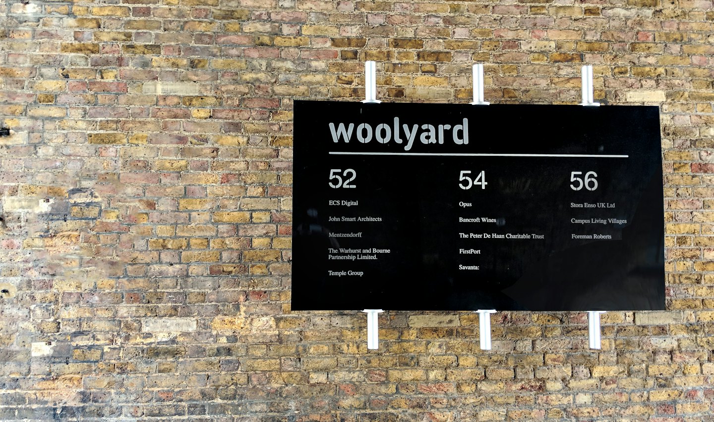 A black business directory sign mounted on a brick wall.